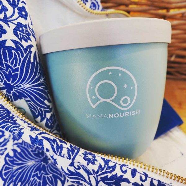 Sage green overnight oats pot tucked into a vivid blue patterned linen bag with a brass zip
