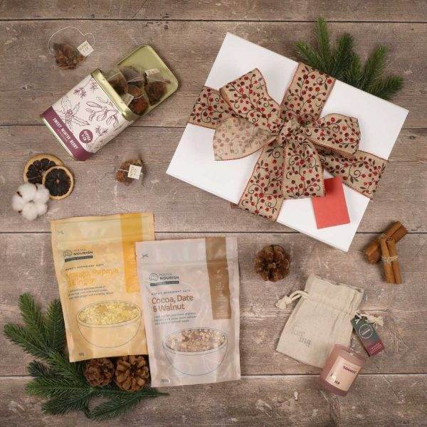 Flat lay photograph of Mama Nourish Christmas gift box with overnight oats, Christmas scented candle and caffeine free winter blend herbal tea